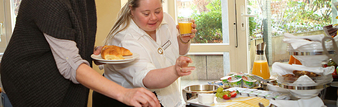 Mitarbeiterin empfiehlt am Frühstücksbuffet